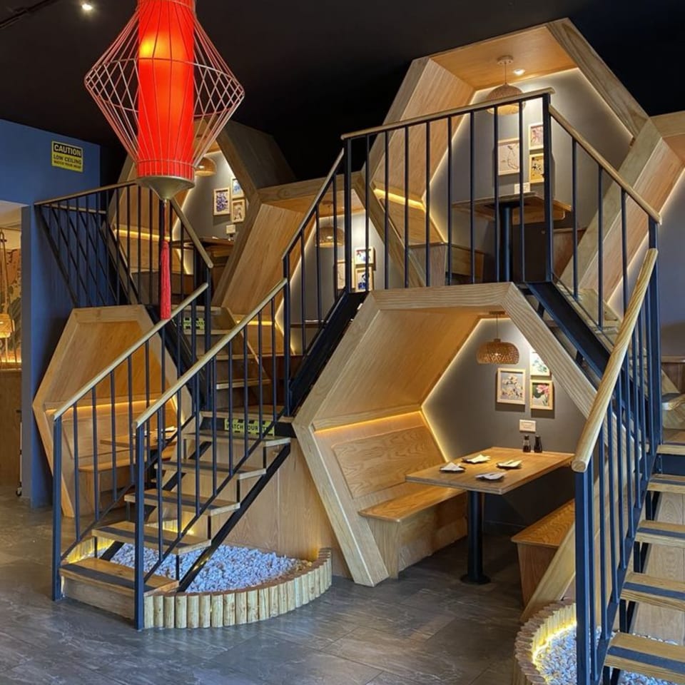 Sakanaya's multi-level dining area features wooden booths, black railings, and a large red lantern.
