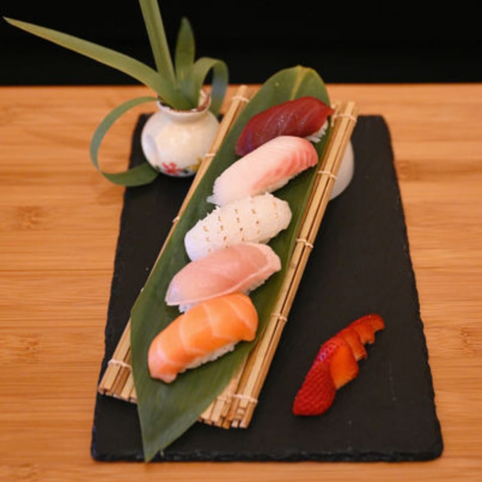 Assortment of Sakanaya nigiri sushi, including tuna, salmon, and white fish, on a bamboo mat.