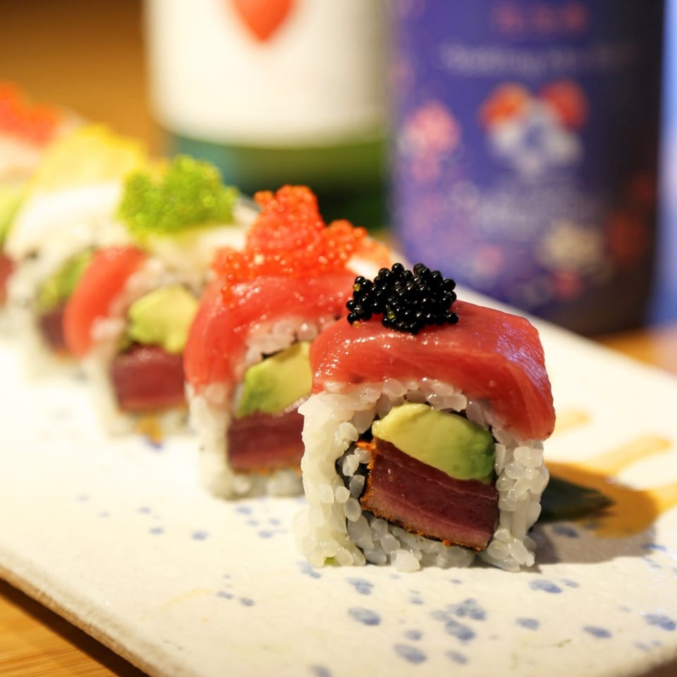 A row of Sakanaya sushi rolls with tuna, avocado, and various colorful roe toppings.