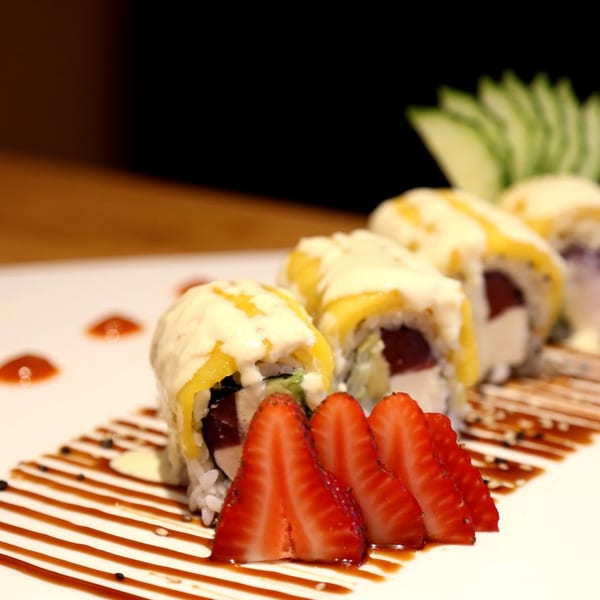 Sakanaya's unique sushi rolls with mango, cream cheese, tuna, and strawberries, drizzled with sauce.