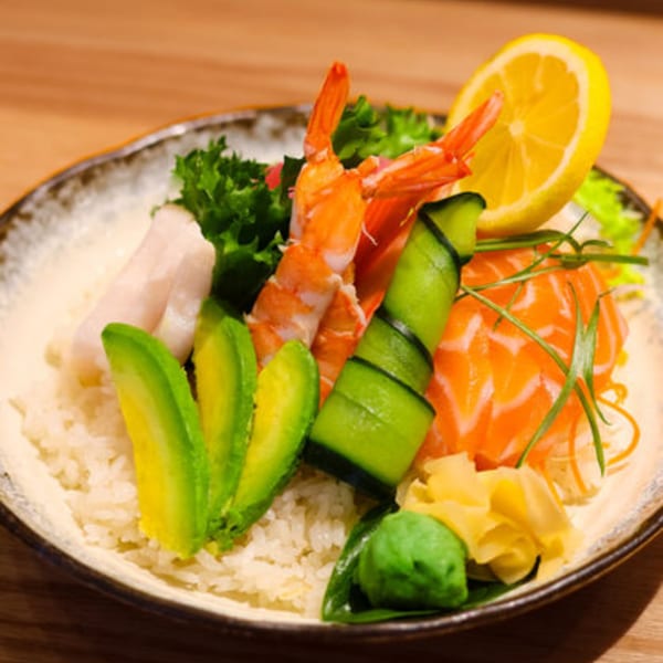 Sakanaya's colorful chirashi bowl with salmon, shrimp, avocado, cucumber, and lemon over rice.