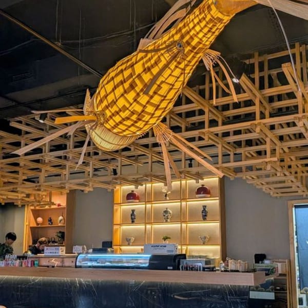 Sakanaya's interior features a large, illuminated fish sculpture hanging above a sushi bar with decorative shelving.